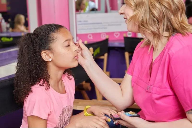 Makeup artist applying light makeup to a young guest